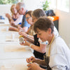 Group of people participating in a ceramics class, with one person in an apron actively working on a task.