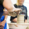 Person working with clay on a pottery wheel in a workshop setting