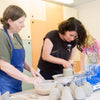 Three women working with clay in a pottery studio.