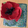 Red flower-shaped object on a textured blue and green fabric background