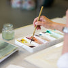 Person painting with watercolors on a table
